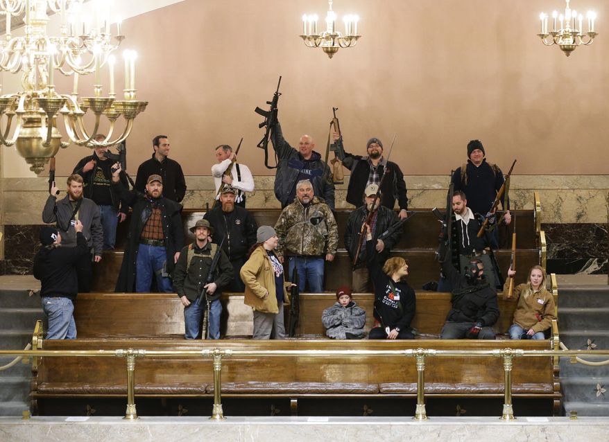 Gun owners display their weapons in the upper gallery of the House chambers, Thursday, Jan. 15, 2015, at the Capitol in Olympia, Wash. The House was not in session when this photo was taken, and members of the group went to the gallery following a protest outside the Legislative building in opposition to the state's Initiative 594, which requires - with only a few exceptions - background checks on all gun sales and transfers. (AP Photo/Ted S. Warren)