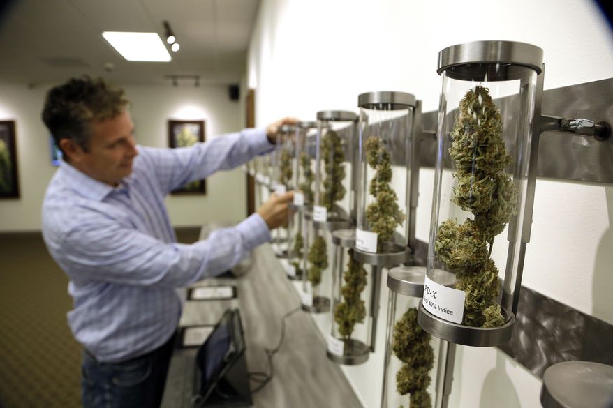 ADVANCE FOR USE SATURDAY JAN. 17, 2015, AND THEREAFTER- File - In this Nov. 5, 2014, file photo, Shane McKee, co-founder of Shango Premium Cannabis medical marijuana dispensary, pulls a sample from their display of cannabis flowers in Portland, Ore. Oregon voters have spoken on marijuana legalization and now legislators want their say. Though the legislative session is more than two weeks away, lawmakers have already introduced more than a dozen bills related to pot. (AP Photo/Don Ryan, File)
