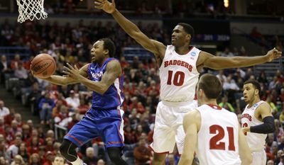 American guard Darius Gardner (0) goes to the basket against Wisconsin forward Nigel Hayes (10) during the first half of a second-round game in the NCAA college basketball tournament Thursday, March 20, 2014, in Milwaukee. (AP Photo/Jeffrey Phelps)
