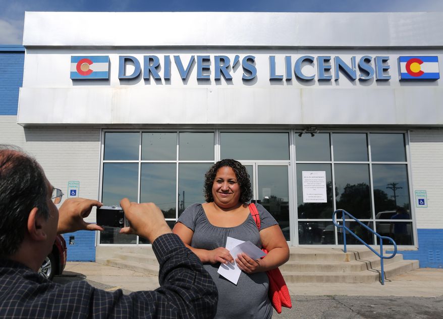 FILE - In this Aug. 1, 2014 file photo, immigrant and longtime resident in the United States Rosalva Mireles is photographed by Jesus Sanchez of Spanish language newspaper El Commercio, after Mireles was processed for her permanent driver's license, and received a temporary one to use until it is ready, at a Department of Motor Vehicles office, in Denver. Colorado Democrats are decrying a Republican decision to not add funding to a program allowing immigrants to get driver's licenses regardless of their legal status. There's been high demand for the program since it launched last year. (AP Photo/Brennan Linsley, file)