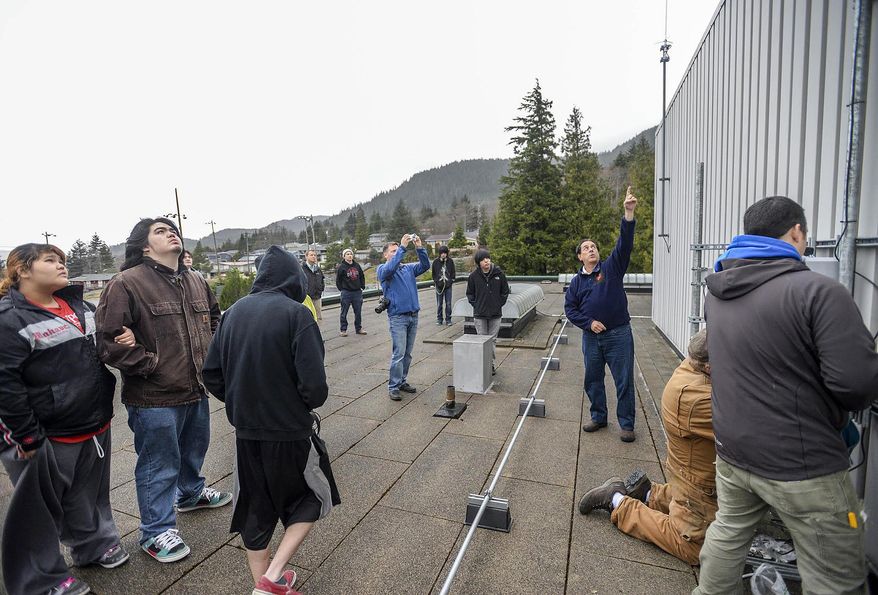 ADVANCE FOR SUNDAY, JAN. 25 AND THEREAFTER This Jan. 16, 2015 photo shows Ron Fortunato, president of Trillium Education, center, as he points to a weather monitor and explains to Ketchikan High School students how it is used to forecast earthquakes in Ketchikan, Alaska. It’s not quite rocket science, but close enough, and closer to home — students in the Tribal Scholars Program began cutting-edge earthquake monitoring research in a partnership with NASA this past week. (AP Photo/Ketchikan Daily News, Taylor Balkom)