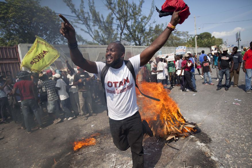 A demonstrator uses wood, gas, fire and salt to call forth a spirit to ask for protection, in a voodoo ceremony before the start of a protest demanding the resignation of President Michel Martelly, in Port-au-Prince, Haiti, Friday, Jan. 23, 2015. The hardline opposition to Martelly has promised a wave of intensified street protests to try and pressure him from office. Martelly took power in 2011 and is due to leave next year. (AP Photo/Dieu Nalio Chery)
