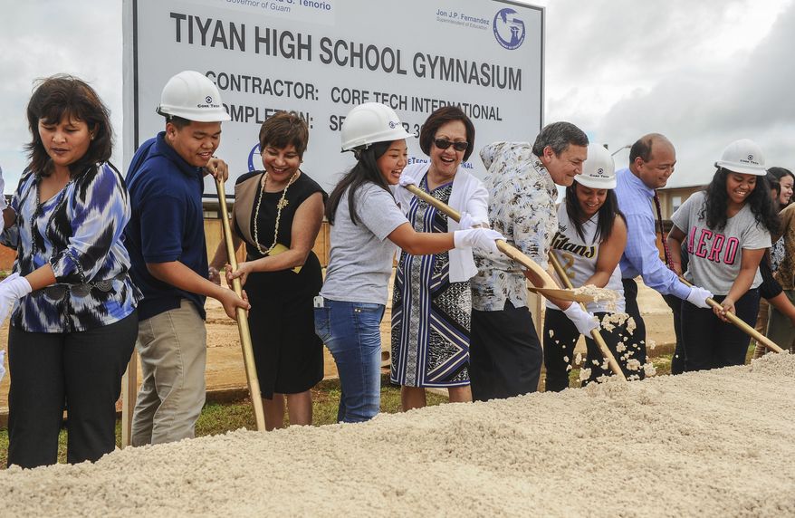 ADVANCE FOR SUNDAY JAN. 25 AND THEREAFTER - In this photo taken Jan. 22, 2015, Associated Body of Students President Janay Masga, center wearing hard hat, and Guam Education Board Vice Chairperson Maria Gutierrez share a shovel as they and others turn soil during the ceremonial groundbreaking of the Tiyan High School gymnasium in Hagatna, Guam. Students at the high school will soon have a new multimillion-dollar gym. The school, which opened in August, broke ground on a new gymnasium, slated to open in September. (AP Photo/Pacific Daily News, Rick Cruz)