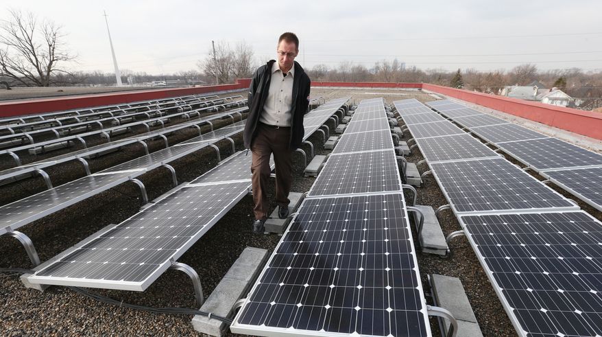 In a Friday, Jan. 23, 2015 photo, Joe Bowling, supervisor for the Englewood Solar Project, looks over solar panels on the roof of the Englewood Christian Church in Indianapolis. Solar energy supporters are pushing back against a bill backed by Indiana's utilities that would change how much credit owners of small-scale solar installations get for the power they generate. (AP Photo/The Indianapolis Star, Mike Fender) NO SALES
