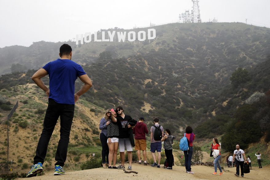 Tourists take their pictures with the Hollywood Sign in the background, Tuesday, Jan. 20, 2015, in Los Angeles. Like pilgrims flocking to a holy shrine, they come from all over the world to pay homage, not to a deity but to something similar - the people they see on TV and in the movies. They are the seekers of the Hollywood Sign, that symbol of the Land of the Rich and Famous. And just like those on pilgrimages to St. Peter's Basilica in Rome or the Acropolis in Greece, they press to get just as close as they can to the immortality the symbol represents. (AP Photo/Jae C. Hong)