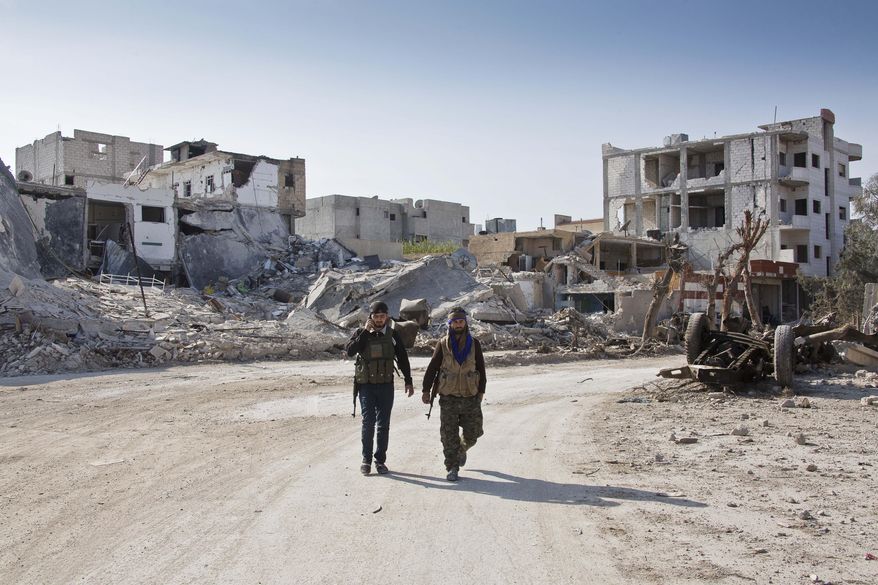 FILE - In this Wednesday, Nov. 19, 2014 file photo, Kurdish People's Protection Units (YPG) soldiers walk near the town entrance circle heading to their strongholds in Kobani, Syria. Syrian activists and Kurdish officials say the extremist Islamic State group has been nearly pushed out of the Syrian border town of Kobani. (AP Photo/Jake Simkin, File)