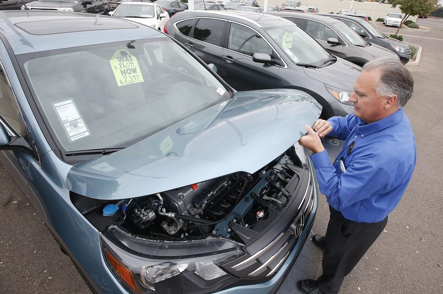FILE - In this Dec. 2, 2014 file photo, Mike Johnson, a sales manager at a Honda car dealership, opens the hood of a Honda CRV SUV in Tempe, Ariz. The Commerce Department releases durable goods orders for January on Tuesday, Jan. 27, 2015. (AP Photo/Ross D. Franklin, File)