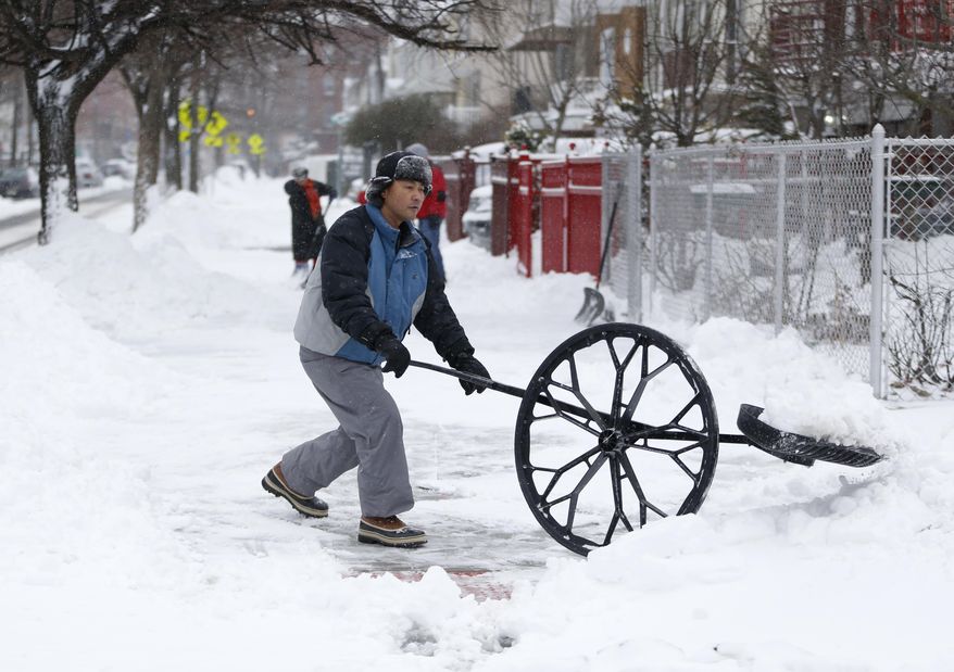 A man uses a shovel with a wheel to clean out a sidewalk following an overnight snowstorm, Tuesday, Jan. 27, 2015, in Jersey City, N.J. A storm packing blizzard conditions spun up the East Coast early Tuesday, pounding coastal eastern Long Island into Maine with high winds and heavy snow. (AP Photo/Julio Cortez)