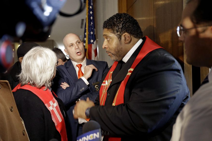 Rev. William Barber, right, President of the North Carolina chapter of the NAACP, speaks with General Assembly Police Lt. Martin Brock, facing, while attempting to enter House Speaker Tim Moore's office at the Legislative building in Raleigh, N.C., Wednesday, Jan. 28, 2015. Religious leaders hand-delivered their moral agenda to representatives' offices Wednesday. North Carolina's NAACP leader challenged new rules concerning public assembly in the State Legislative Building as part of protests on Wednesday targeting legislative policies by GOP leaders who control both chambers. (AP Photo/Gerry Broome)