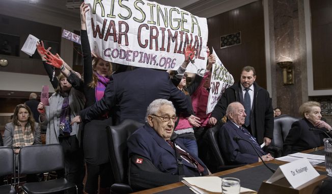 Protesters interrupt the start of a Senate Armed Services hearing, on Capitol Hill in Washington, Thursday, Jan. 29, 2015,  as they shout at former Secretary of State Henry A. Kissinger, center, joined by fellow former State Department heads George P. Shultz and Madeleine K. Albright. The upheaval came as members of an anti-war group Code Pink called the 91-year-old Kissinger a war criminal. (AP Photo/J. Scott Applewhite)