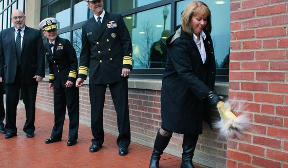 Vice Adm. Willy Hilarides (center) watches his wife Beverly break a bottle against the wall during the reopening ceremony for the Naval Sea Systems Command&#39;s headquarters building at the Washington Navy Yard. On the far left is Rear Admiral Katherine L. Gregory. The building was the site of the shooting rampage on Sept. 16, 2013. (U.S. Navy)