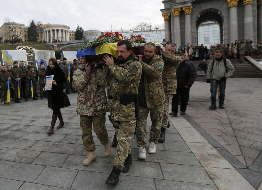 Ukrainian soldiers carry the coffin bearing the body of serviceman Ruslan Baburov, who was killed in fighting against Russian-backed separatists, during a commemoration ceremony in Independence Square in Kiev, Ukraine, on Monday, Feb. 2, 2015. Ukraine's government said Sunday that 13 of its troops were killed and another 20 wounded in a day of fighting across the east. (AP Photo/Sergei Chuzavkov)