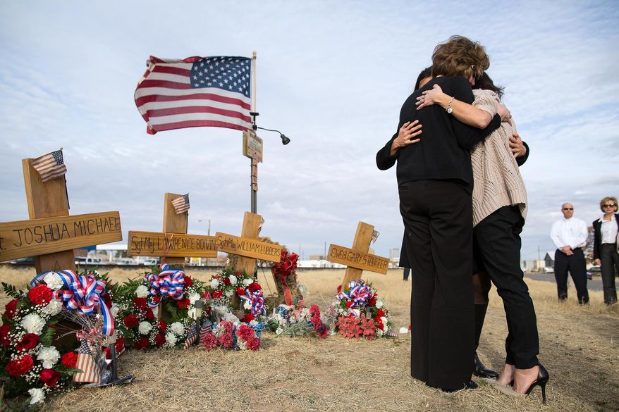 FILE - In this Jan. 29, 2015 file photo, Tiffany Lubbers, back, Angela Boivin, left, and Catherine Stouffer, rigth, widows of veterans killed in the 2012 crash of a freight train and a veterans' parade float, embrace at a makeshift memorial in Midland, Texas. A ruling is expected Monday, Feb. 2, 2015 from a Midland judge on whether to dismiss a lawsuit arising from the crash that killed four veterans and injured about a dozen. Twenty-six people reached a confidential settlement this month with Union Pacific. (AP Photo/The Odessa American, Courtney Sacco, File)