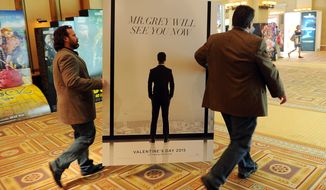 Sheldon Domke (left) and Adam Mast move an advertisement for the upcoming film &quot;Fifty Shades of Grey&quot; during the second day of CinemaCon 2014 in Las Vegas. (Associated Press)