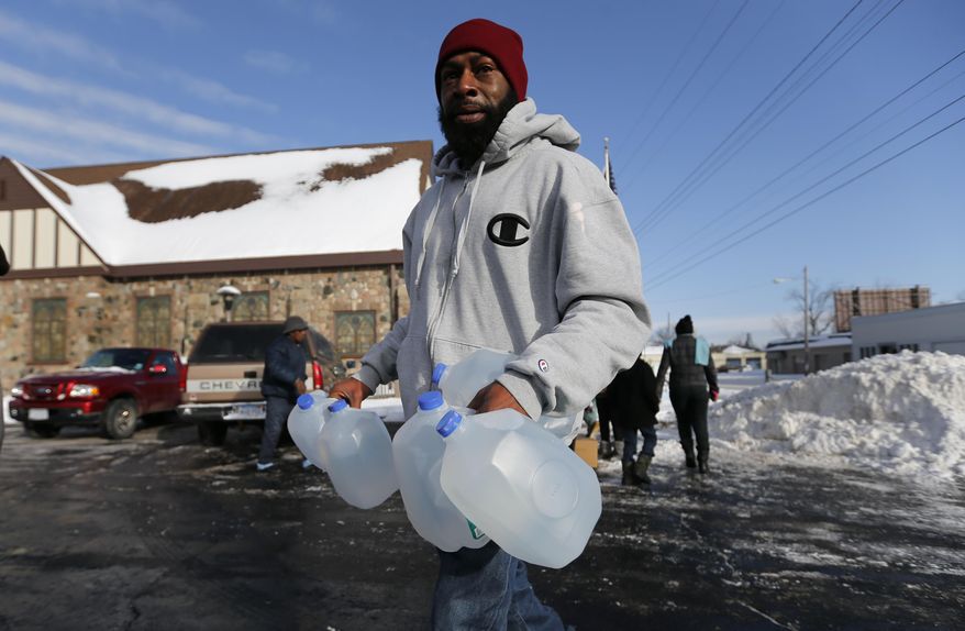 Lemott Thomas carries free water being distributed at the Lincoln Park United Methodist Church in Flint, Mich., Tuesday, Feb. 3, 2015. The city gets tap water from the Flint River, but residents have complained about the smell, taste and appearance. The city says the water is safe to drink. The federal government, however, has cited Flint for high levels of a disinfectant byproduct. (AP Photo/Paul Sancya)