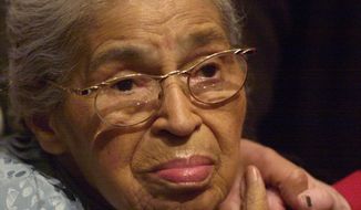 Civil rights pioneer Rosa Parks holds the hand of a well-wisher at a ceremony honoring the 46th anniversary of her arrest for civil disobedience, at the Henry Ford Museum in Dearborn, Mich., in this Saturday, Dec. 1, 2001, file photo. Beginning Wednesday, Feb. 4, 2015, at the Library of Congress, researchers and the public will have full access to Parks’ archive of letters, writings, personal notes and photographs for the first time. (AP Photo/Paul Warner, File)