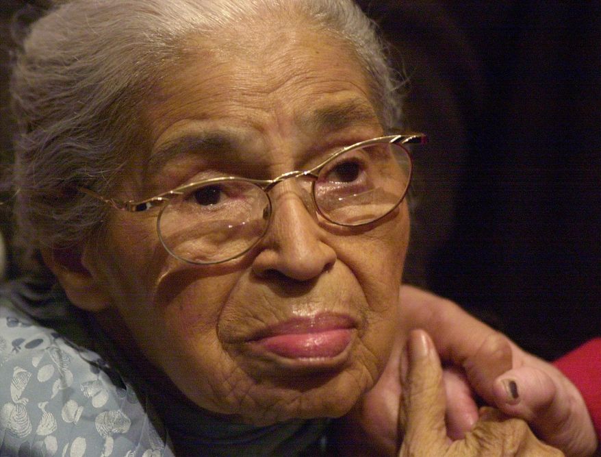 Civil rights pioneer Rosa Parks holds the hand of a well-wisher at a ceremony honoring the 46th anniversary of her arrest for civil disobedience, at the Henry Ford Museum in Dearborn, Mich., in this Saturday, Dec. 1, 2001, file photo. Beginning Wednesday, Feb. 4, 2015, at the Library of Congress, researchers and the public will have full access to Parks’ archive of letters, writings, personal notes and photographs for the first time. (AP Photo/Paul Warner, File)