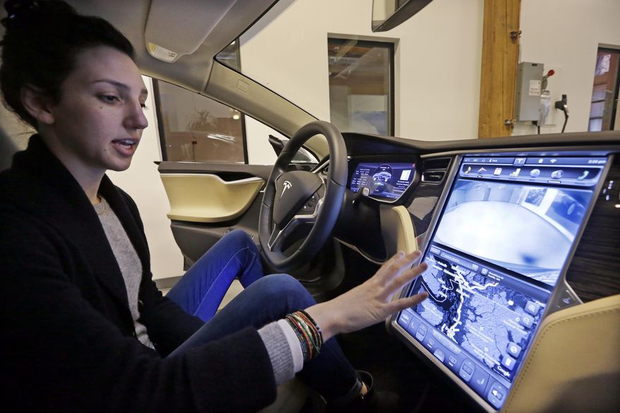 Tesla product specialist Kat Brand explains the control panel on the electric car at a dealership for the vehicle, Wednesday, Feb. 4, 2015, in Seattle. Washington state's Senate is still figuring out policy on the electric cars gaining popularity, Tesla among them. Bills discussed in hearings this week would extend the sales/use tax exemption for clean-fuel vehicles and require King/Pierce/Thurston counties to give incentives to builders for adding electric-charging stations to projects. (AP Photo/Elaine Thompson)