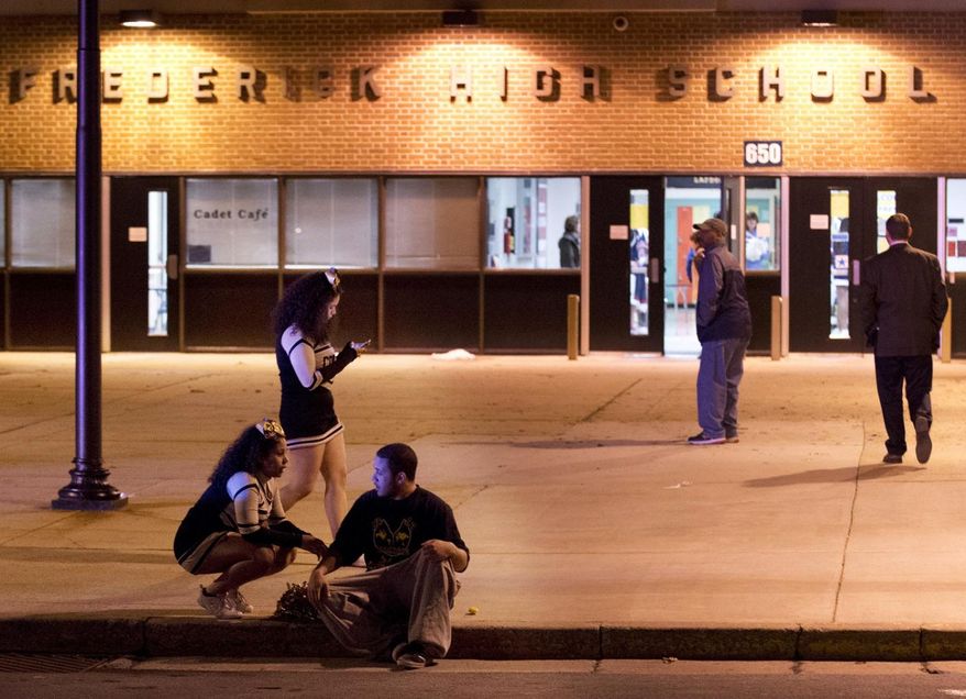 People gather outside the entrance to Frederick High School following a shooting in Frederick, Md., Wednesday, Feb. 4, 2015. Police and school officials said students were shot outside the school while a basketball game was being played inside. (AP Photo/The Frederick News-Post, Bill Green)