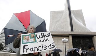 Marti Kashuba holds up a sign outside of St. Mary&#x27;s Cathedral in San Francisco, Friday, Feb. 6, 2015. The Roman Catholic archbishop of San Francisco is getting pushback from some parents, students and teachers at parochial schools after unveiling faculty handbook language calling on teachers to lead their public and professional lives consistently with church teachings on homosexuality, same-sex marriage, abortion, birth control and other behaviors he describes as evil. (Associated Press) **FILE**