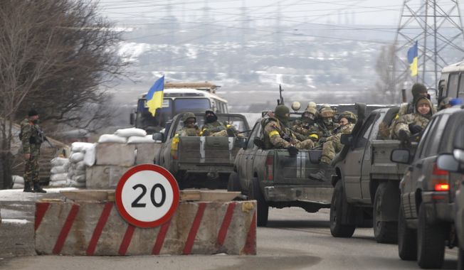 Ukrainian government troops sit in the back of pick-up trucks as they pass a checkpoint near the town of Mariupol, Ukraine, Tuesday, Feb. 10, 2015. The intense fighting, which the U.N. says has killed more than 5,300 people since April, comes ahead of a crucial summit including Western leaders on Wednesday as well as peace talks later Tuesday. The volunteer Azov battalion said on social media on Tuesday that it captured several villages northeast of the strategic port of Mariupol, pushing the rebels closer to the border with Russia. (AP Photo/Petr David Josek)
