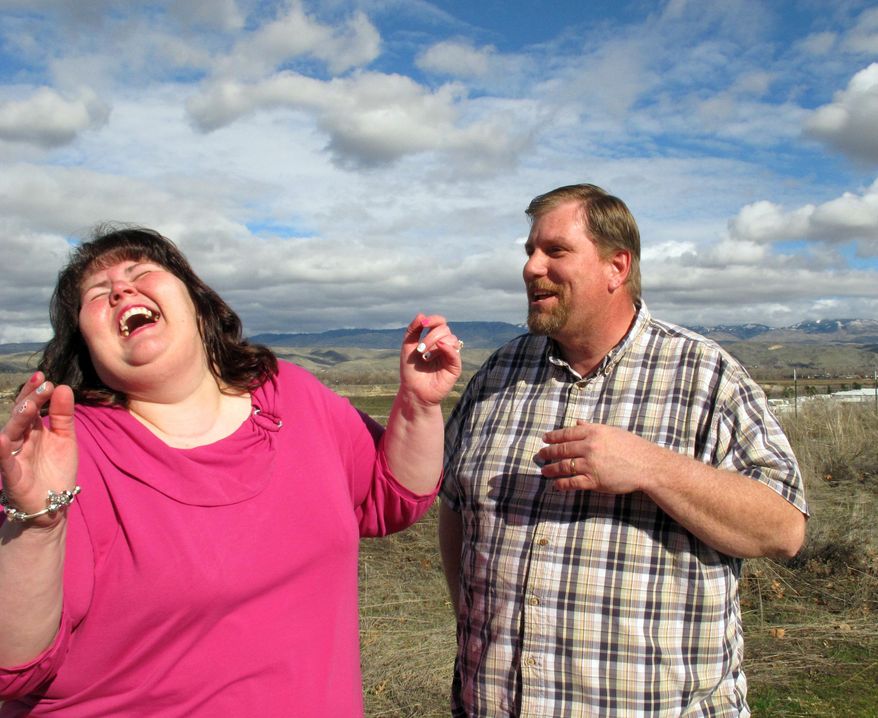 In this Tuesday, Feb. 10, 2015 photo, Michelle and Robert Philippi laugh as they stand together for a photograph in Boise, Idaho. One day, her mother came home from community college and said, "That guy in that class, he’s so obnoxious, he’s so loud _ and here’s his phone number. I think you’d be perfect together." So Michelle called "that guy" _ Robert _ and he invited her to go fishing. (AP Photo/Rebecca Boone)