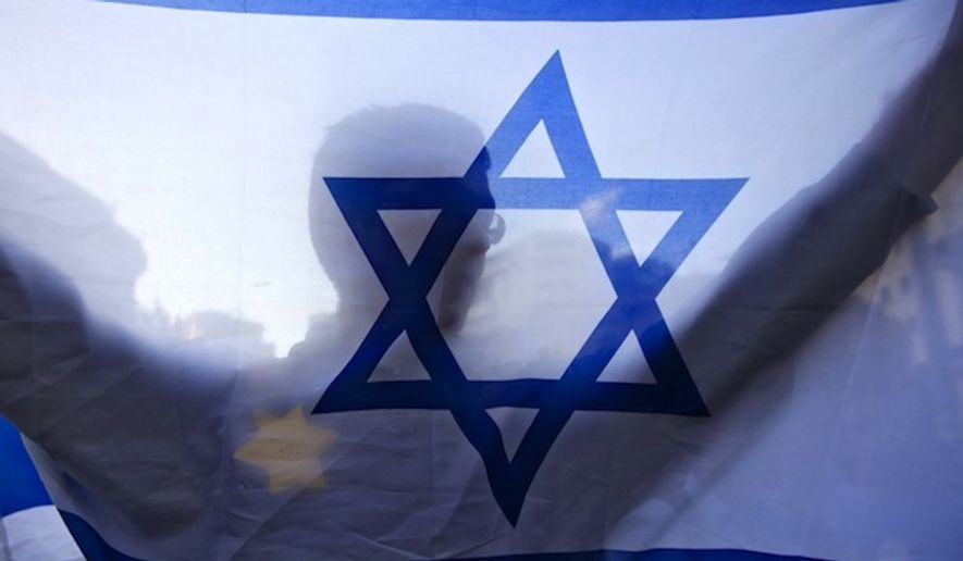 An Israeli holds a flag and wears a Star of David patch resembling the one Jews were forced to wear in Nazi Germany during a demonstration in Jerusalem. (Associated Press/Sebastian Scheiner) ** FILE **