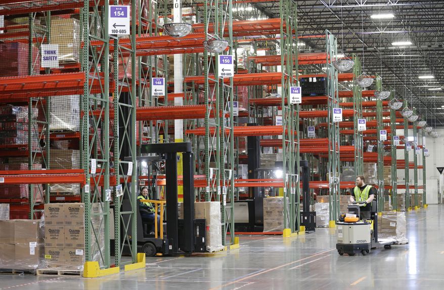 Workers operate forklifts along a row of inventory shelves, Friday, Feb. 13, 2015, during a media tour of the new Amazon.com fulfillment center in DuPont, Wash. The center is one of 50 around the country and three in the Puget Sound area that process and ship Amazon customer orders using a mix of robotic technology and human employees. (AP Photo/Ted S. Warren)