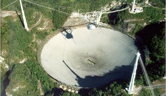 This undated handout photo provided by Seth Shostak, SETI Institute, shows the Arecibo radio telescope in Puerto Rico. The world’s largest single antenna, it has a million watt transmitter. Astronomers have their own cosmic version of the single person’s Valentine’s Day dilemma: Do you wait for that interesting person to call you or do you make the call yourself and risk getting shot down. Their version involves E.T. Instead of love, astronomers are looking for life out there in the universe. For decades, astronomers have sat by their telescopes, listened and waited for a call from E.T. only to be left alone. So now some of them want to aim their best radars and lasers out to the sky to say “We’re here, call us” to the closest few thousand worlds. They can bring us all sorts of new technologies and answers to burning questions, some hope. (AP Photo/Seth Shostak, SETI Institute)  **FILE**