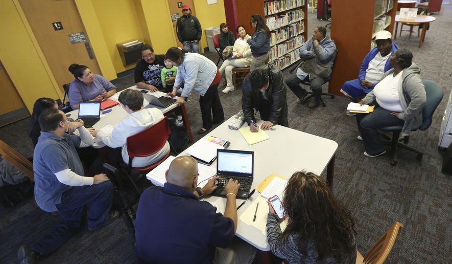 In this photo made Thursday, Feb. 12, 2015, Affordable Care Act navigators hold an enrollment event at the Fort Worth Public Library in Fort Worth, Texas. (AP Photo/LM Otero)
