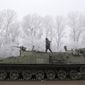 Ukrainian government soldier walks atop of his armored vehicle on the road between the towns of Dabeltseve and Artemivsk, Ukraine, Sunday, Feb. 15, 2015. (AP Photo/Petr David Josek)