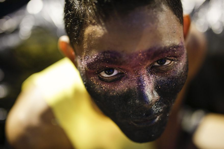 A reveler from the Sao Clemente samba school poses for a photo as he waits for the start of the Carnival parade at the Sambadrome in Rio de Janeiro, Brazil, Monday, Feb. 16, 2015. (AP Photo/Felipe Dana)