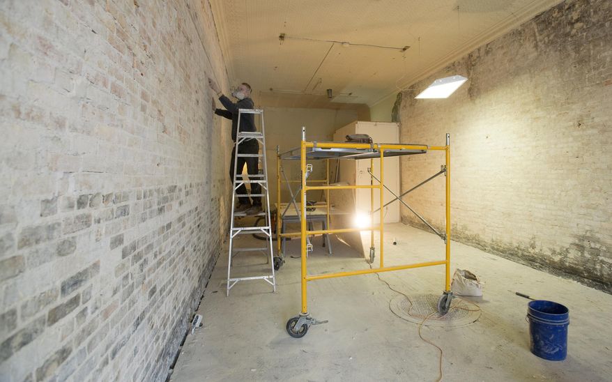 Garrett Williams, 21, scrapes plaster off the bricks of a wall at the new Mr. Van's Shoe Repair in Old Town Saginaw, Feb. 11, 2015. The original Mr Van's in Saginaw Township's Green Acres Plaza closed last year and Williams purchased the business. Williams and a construction crew are renovating the building on Court exposing and cleaning the original floor and brick walls with plans to open on April 1. (AP Photo/The Saginaw News, Jeff Schrier) ALL LOCAL TELEVISION OUT; LOCAL TELEVISION INTERNET OUT