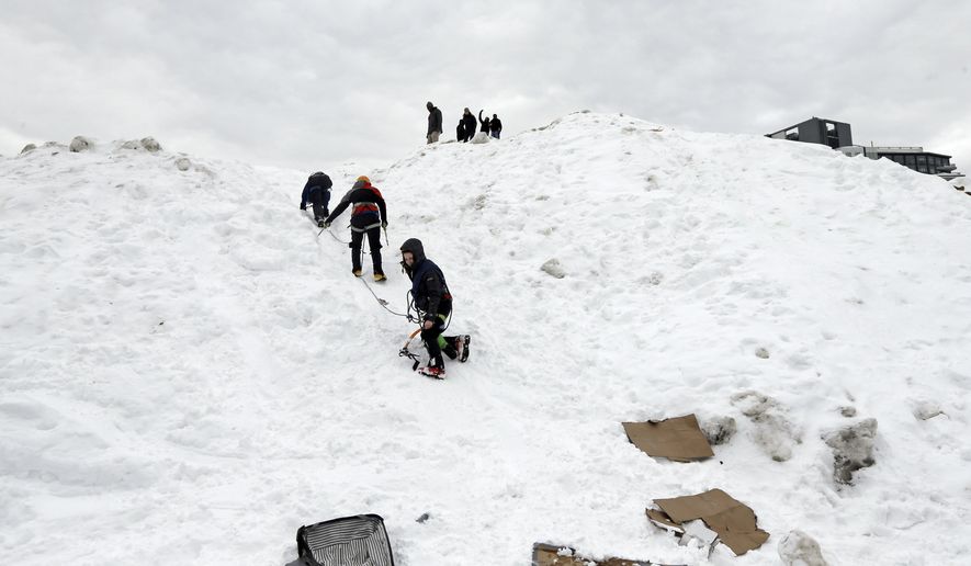 Three students from the Massachusetts Institute of Technology jokingly use mountaineering gear to make their way down from a massive snow pile on the MIT campus in Cambridge, Mass., Wednesday, Feb. 18, 2015. The mountain of excess snow has been dubbed the "Alps of MIT" and is being used for climbing, sledding and posing. (AP Photo/Elise Amendola)