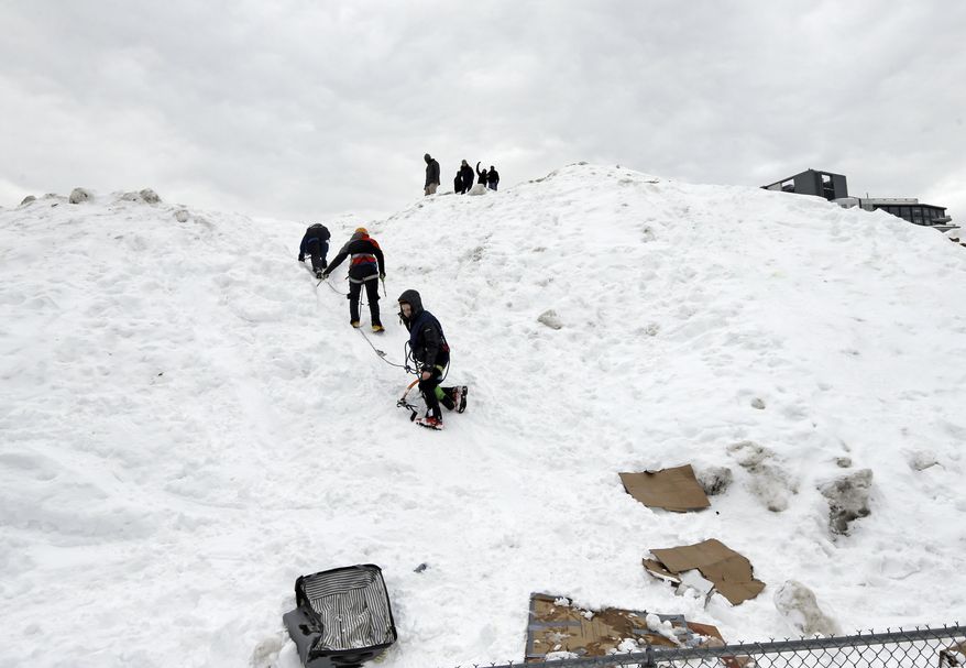 Three students from the Massachusetts Institute of Technology jokingly use mountaineering gear to make their way down from a massive snow pile on the MIT campus in Cambridge, Mass., Wednesday, Feb. 18, 2015. The mountain of excess snow has been dubbed the "Alps of MIT" and is being used for climbing, sledding and posing. (AP Photo/Elise Amendola)