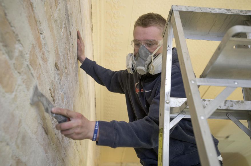 Garrett Williams, 21, scrapes plaster off the bricks of a wall at the new Mr. Van's Shoe Repair in Old Town Saginaw, Feb. 11, 2015. The original Mr Van's in Saginaw Township's Green Acres Plaza closed last year and Williams purchased the business. Williams and a construction crew are renovating the building on Court exposing and cleaning the original floor and brick walls with plans to open on April 1. (AP Photo/The Saginaw News, Jeff Schrier) ALL LOCAL TELEVISION OUT; LOCAL TELEVISION INTERNET OUT
