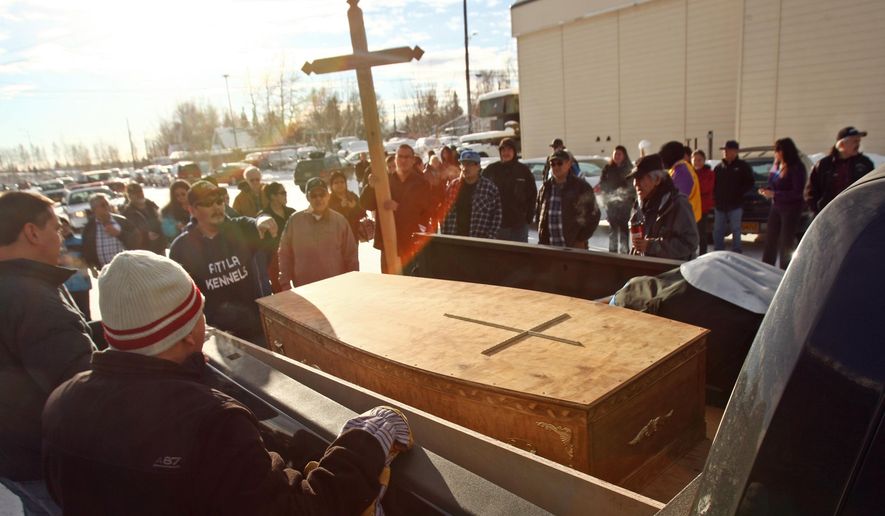 In this photo taken Feb. 17, 2015, a casket and cross are loaded into a pickup truck to be taken to the airport for transport during the memorial service Athabascan sprint racing champion George Attla Jr. at the the Chief David Salmon Tribal Hall in Fairbanks, Alaska. Attla died over the weekend at age 81. (AP Photo/The Fairbanks Daily News-Miner, Eric Engman)