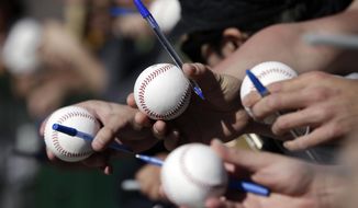 San Francisco Giants fans holds baseballs and pens in hopes for getting an autograph as players arrive for spring training baseball workouts Wednesday, Feb. 18, 2015, in Scottsdale, Ariz. Giants pitchers and catchers have their first official workout scheduled for Thursday. (AP Photo/Darron Cummings)