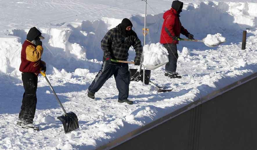 Workers clear snow from a roof in Boston, Monday, Feb. 16, 2015. New England remained bitterly cold Monday after the region's fourth winter storm in a month blew through. (AP Photo/Michael Dwyer)