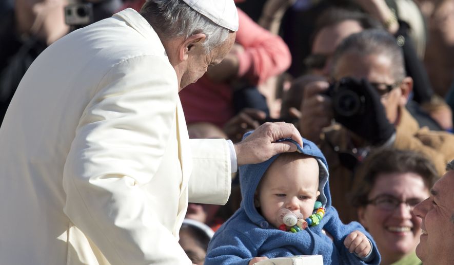 Pope Francis adjusts a baby's hood as he arrives for his weekly general audience, in St. Peter's Square, at the Vatican, Wednesday, Feb. 18, 2015. (AP Photo/Andrew Medichini)