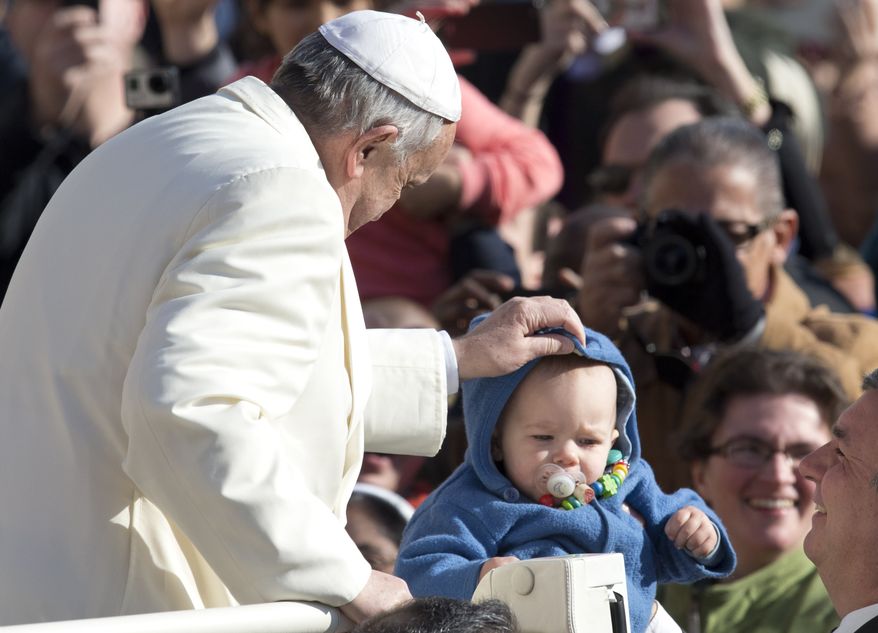 Pope Francis adjusts a baby's hood as he arrives for his weekly general audience, in St. Peter's Square, at the Vatican, Wednesday, Feb. 18, 2015. (AP Photo/Andrew Medichini)