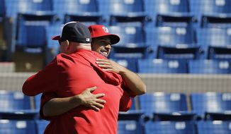 Washington Nationals pitcher Gio Gonzalez, right, embraces manager Matt Williams while crossing paths doing media interviews as pitchers and catchers officially report for spring training baseball, Thursday, Feb. 19, 2015, in Viera, Fla. (AP Photo/David Goldman)