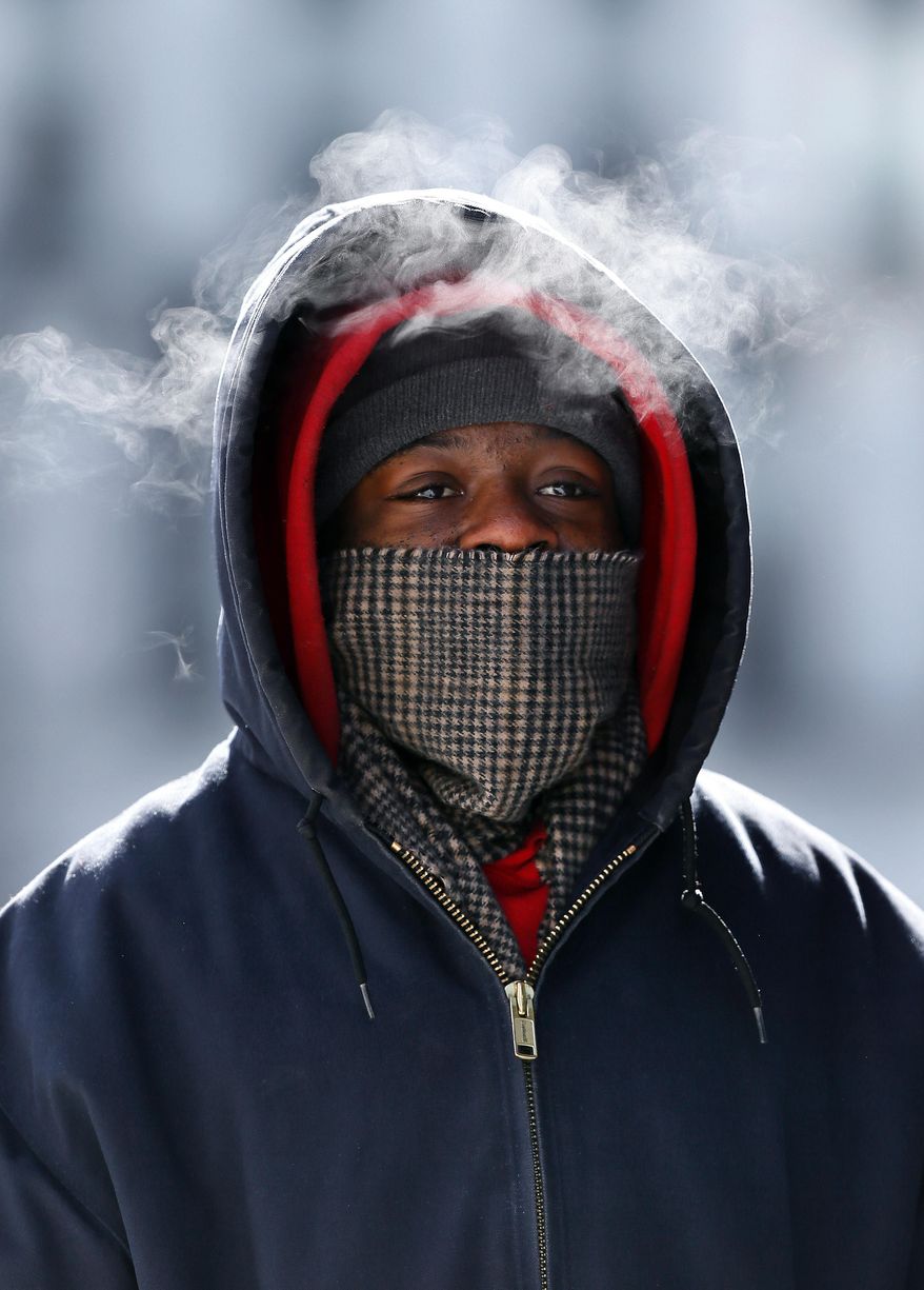 Korey King's breath is visible as he walks in Detroit Thursday, Feb. 19, 2015. The National Weather Service says the temperature dropped to 5 below zero Thursday morning at Detroit Metropolitan Airport in Romulus, one degree below the previous Detroit record for the date from 1936. (AP Photo/Paul Sancya)