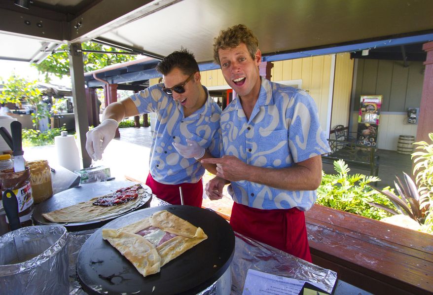 ** ADVANCE FOR SATURDAY FEB. 21 AND THEREAFTER ** In this photo taken Feb. 18, 2015, Bryce Campbell, left, and Jonathan Pajot, right, cook crepes inside their “Delice Crepes" food booth during the unveiling of the new Hukilau Marketplace at the Polynesian Cultural Center in Laie, Hawaii. The Polynesian Cultural Center always has been predominantly an all-day attraction with its re-created island villages, buffet and luau offerings, and elaborate evening show. But in the most ambitious expansion project since the center opened in Laie in 1963, the PCC has a new 119,000-square foot Hukilau Marketplace, which will feature more than 40 stores, eateries and attractions. (AP Photo/Honolulu Star-Advertiser, Dennis Oda)