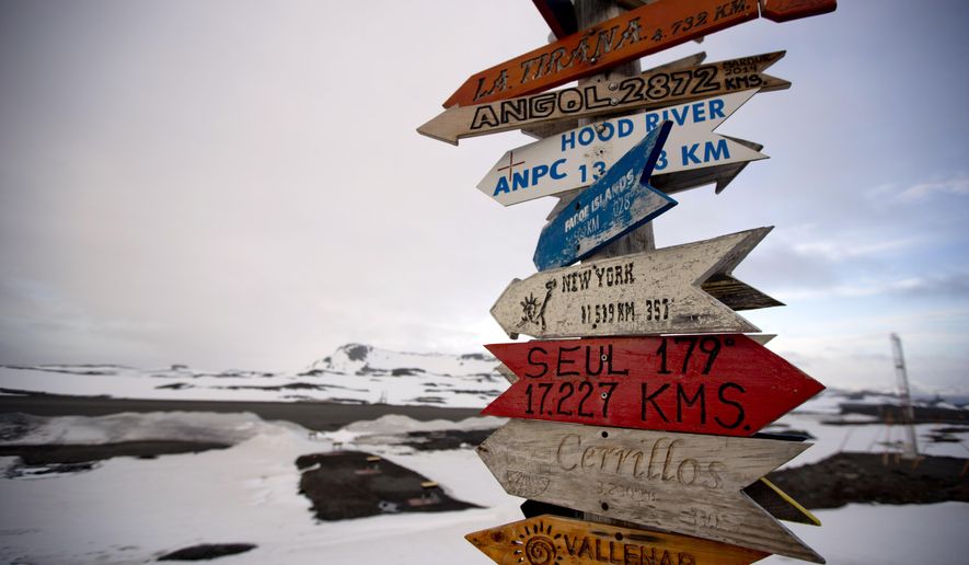 In this Jan. 20, 2015 photo, wooden arrows show the distances to various cities near Chile's Escudero station on King George Island, Antarctica. Thousands of scientists come to Antarctica for research. There are also non-scientists, chefs, divers, mechanics, janitors and the priest of the world’s southernmost Eastern Orthodox Church on top of a rocky hill at the Russian Bellinghausen station. (AP Photo/Natacha Pisarenko)