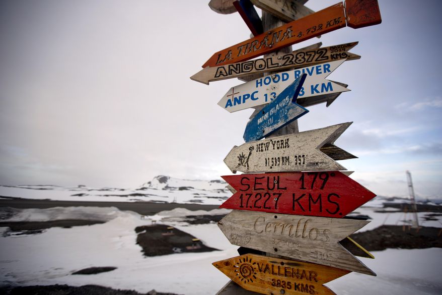 In this Jan. 20, 2015 photo, wooden arrows show the distances to various cities near Chile's Escudero station on King George Island, Antarctica. Thousands of scientists come to Antarctica for research. There are also non-scientists, chefs, divers, mechanics, janitors and the priest of the world’s southernmost Eastern Orthodox Church on top of a rocky hill at the Russian Bellinghausen station. (AP Photo/Natacha Pisarenko)