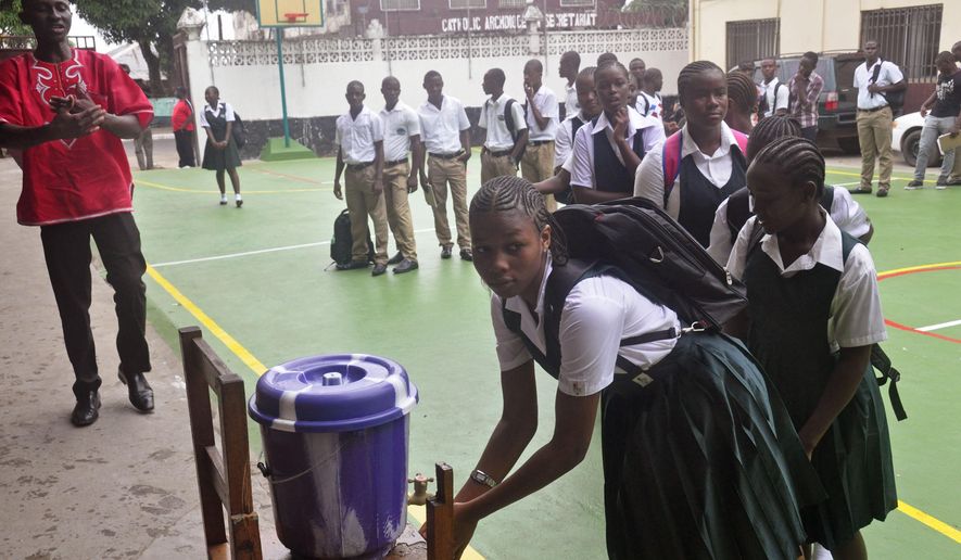 Liberian school children wash their hands before entering their classrooms as part of the Ebola prevention measures at Cathedral High School as students arrive in the morning to attend class in Monrovia, Liberia, Monday, Feb. 16, 2015. Students in Liberia began returning to the classroom Monday after a six-month closure during the Ebola epidemic that left thousands dead in this West African country.(AP Photo/Abbas Dulleh)
