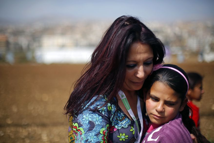 Fatima, 12, is hugged by  Maria Assi, director of Lebanese NGO "Beyond" in the Fadaya Camp some 25 miles east of Beirut, Sunday March 9, 2014. Fatima comes from Bab Dhour in Idlib, Syria. Her dad died before the war started. Fatima and her mom came to the camp a year ago. Two months ago, when a major winter storm hit the Bekaa valley, Fatima's mother died.  Fatima now calls Maria "mama" and Maria makes sure that Fatima participates in classes treating children with emotional trauma and depression. (AP Photo/Jerome Delay)