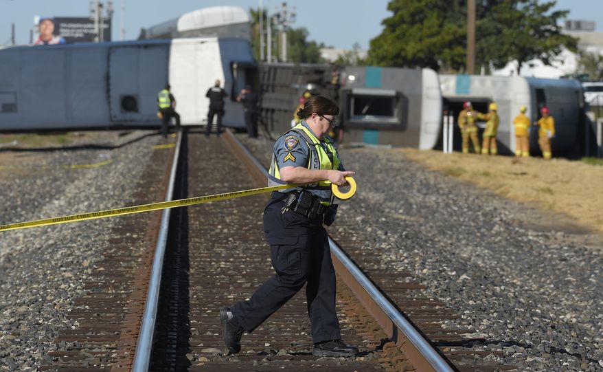In this file photo, a police officer stretches caution tape across railroad tracks near cars from a Metrolink passenger train that derailed Tuesday, Feb. 24, 2015, in Oxnard, Calif. The Orange County Register reported on April 21, 2018, that a 71-year-old was fatally struck by a Metrolink train nearby a campground where he and his wife were vacationing. (AP Photo/Mark J. Terrill) **FILE**