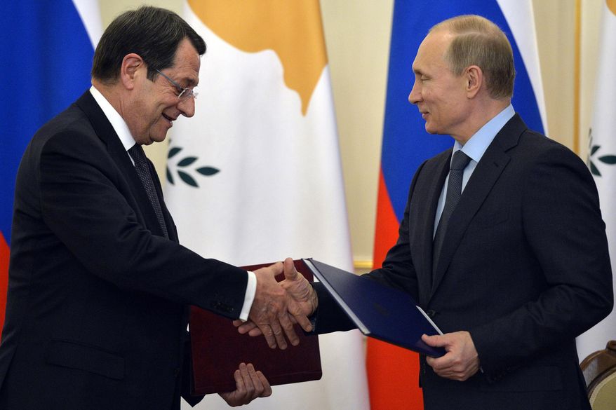 Russian President Vladimir Putin, right, and Cyprus' President Nicos Anastasiades shake hands as they exchange documents at a signing ceremony in the Novo-Ogaryovo residence outside Moscow, Russia, Wednesday, Feb. 25, 2015. Russia and Cyprus have signed a military cooperation agreement that would allow Russian navy ships to make regular port calls on the island. (AP Photo/Yuri Kadobnov, Pool)